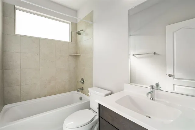 a bathroom with a bathtub shower sink vanity mirror and toilet