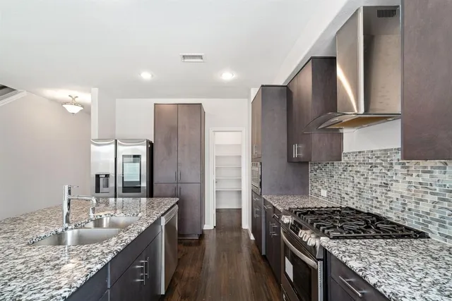 a kitchen with granite countertop a sink stove and refrigerator