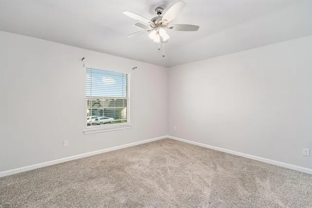 an empty room with a window and a ceiling fan
