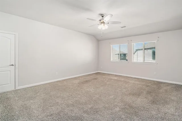 an empty room with windows and chandelier fan