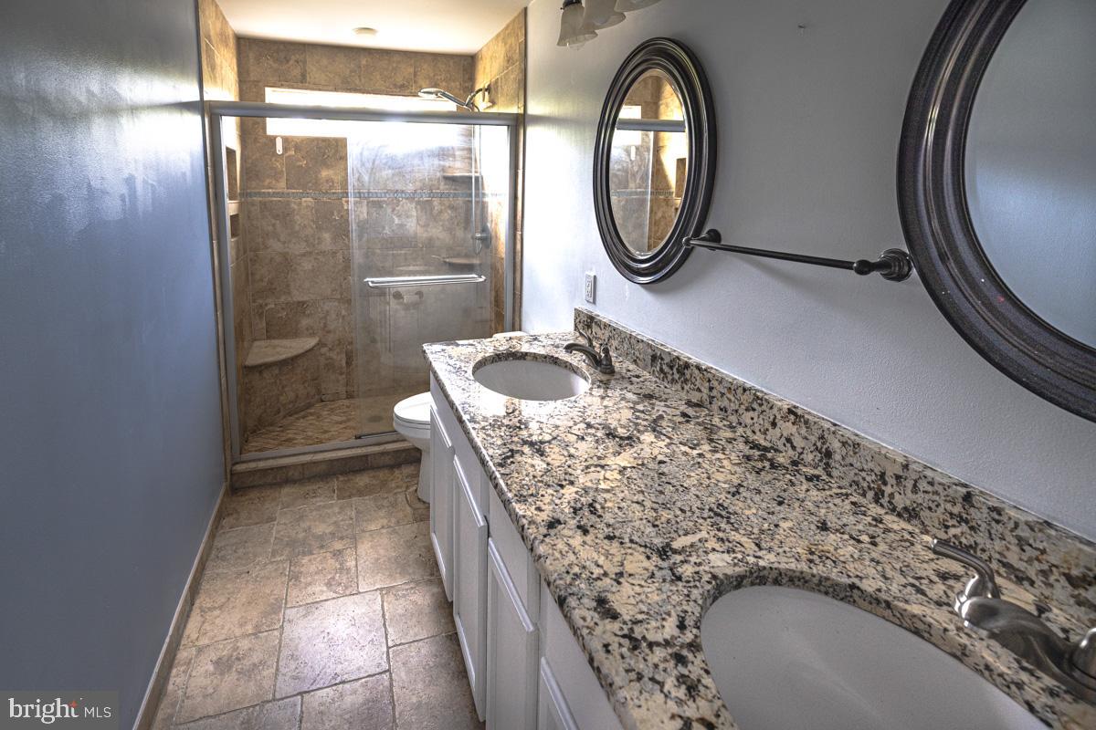 892 Estates Boulevard Hamilton, NJ 08690 - Photo 18 of 36 a bathroom with a granite countertop sink a mirror and shower