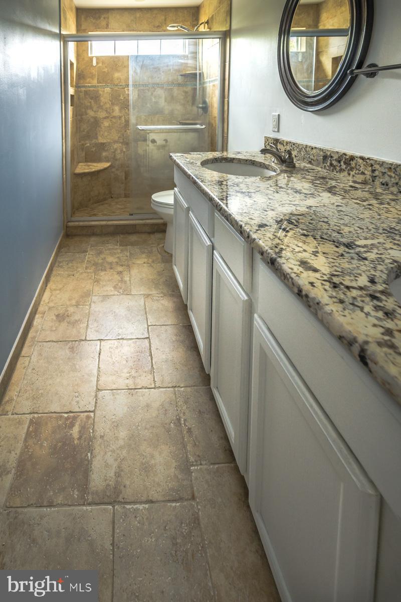 892 Estates Boulevard Hamilton, NJ 08690 - Photo 20 of 36 a bathroom with a granite countertop sink a mirror and a shower