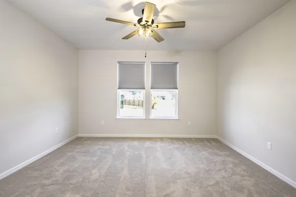 an empty room with windows and fan