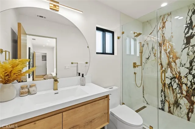 a bathroom with a sink toilet vanity and shower