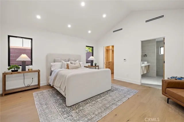 a spacious bedroom with a bed a couch and potted plant