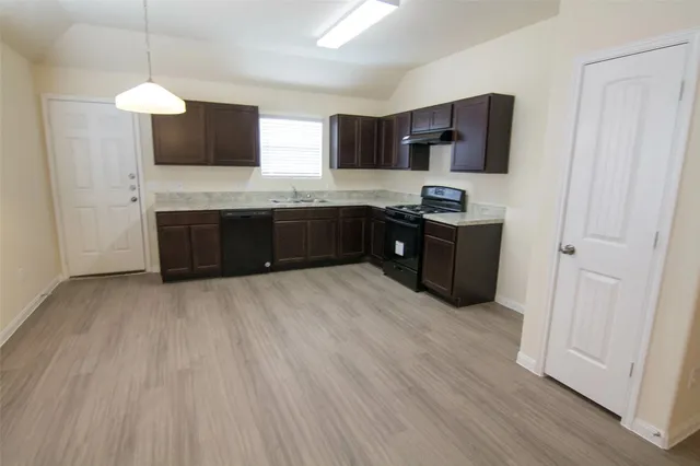 a kitchen with stainless steel appliances granite countertop a stove a sink dishwasher and a refrigerator with wooden floor