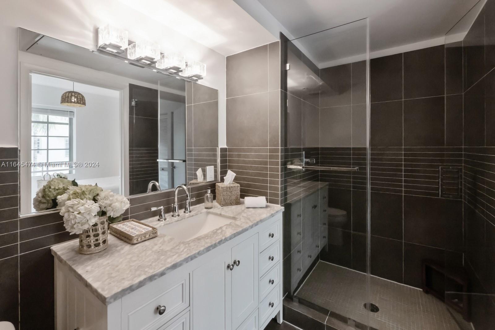 435 21st Street, Unit 310 Miami Beach, FL 33139 - Photo 12 of 28 a bathroom with a granite countertop sink a mirror and a shower
