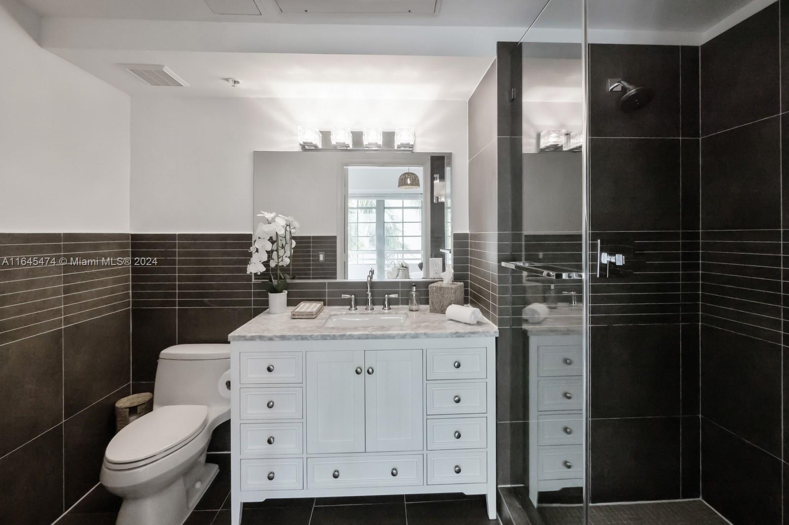435 21st Street, Unit 310 Miami Beach, FL 33139 - Photo 13 of 28 a bathroom with a granite countertop sink toilet and mirror