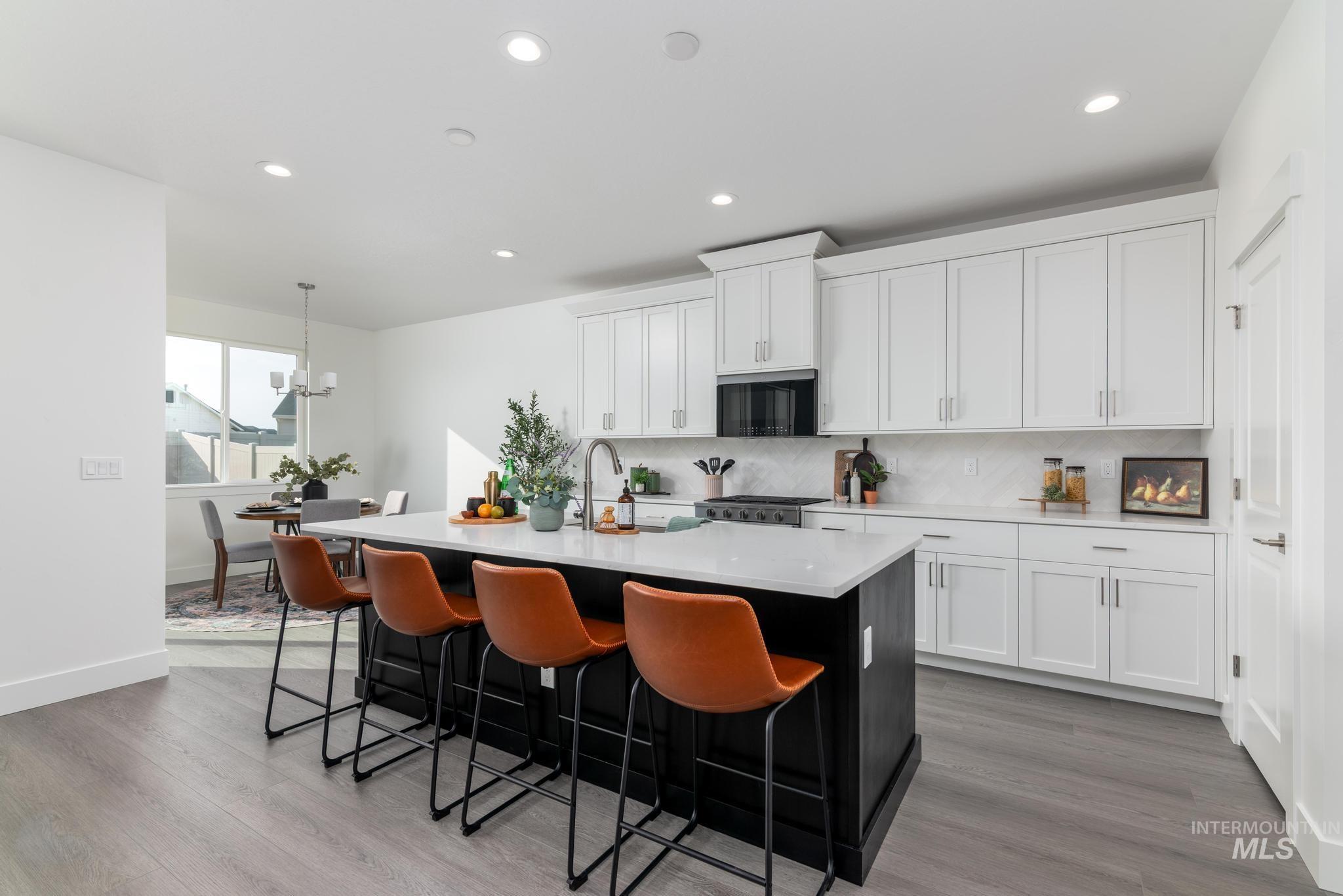 822 West Bay Street Middleton, ID 83644 - Photo 4 of 11 Kitchen with a kitchen breakfast bar, a center island with sink, dark wood-style flooring, dual tone cabinetry, and light stone countertops