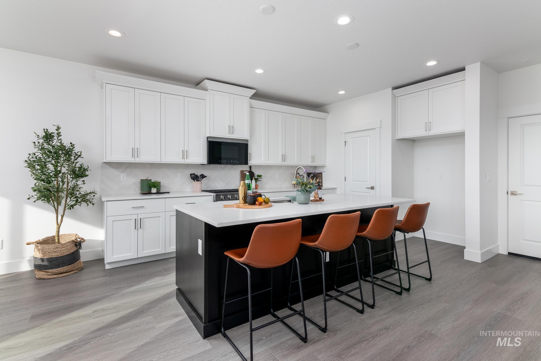 822 West Bay Street Middleton, ID 83644 - Photo 5 of 11 Kitchen featuring an island with sink, light wood finished floors, a kitchen breakfast bar, recessed lighting, and backsplash