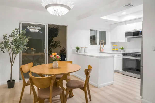 a kitchen with a dining table chairs and refrigerator