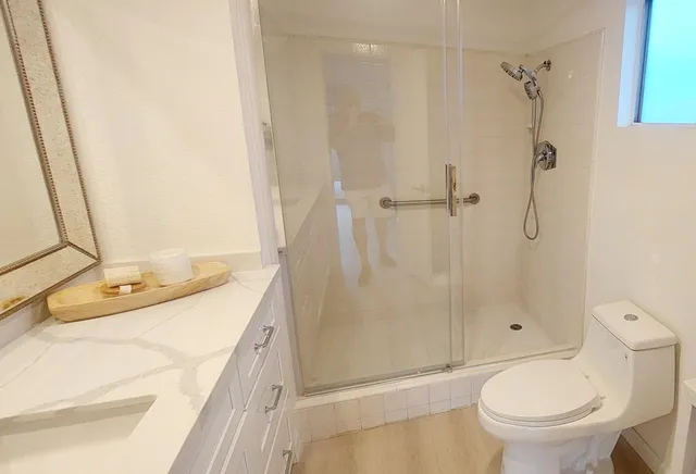 a bathroom with a granite countertop sink toilet and shower