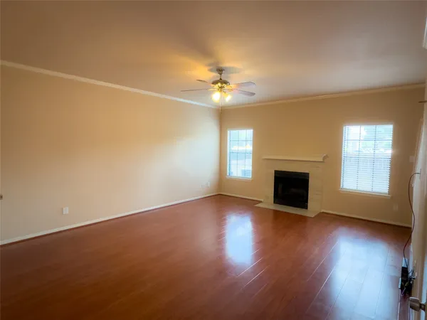 an empty room with wooden floor fireplace and windows