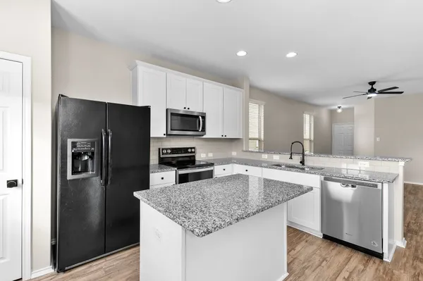 a kitchen with a sink a microwave a refrigerator and cabinets