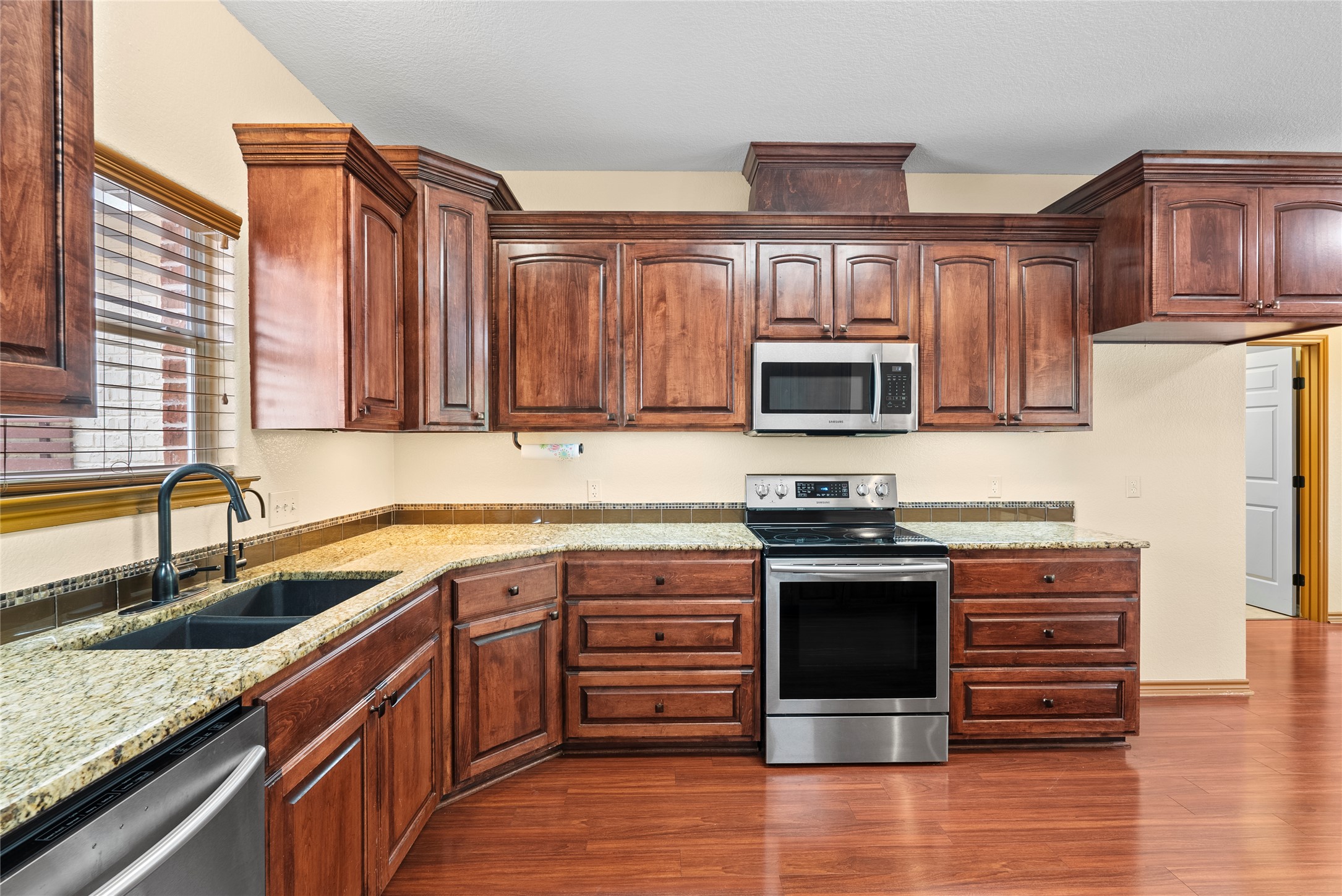 330 Arbors Circle Elgin, TX 78621 - Photo 5 of 37 A well-appointed kitchen features rich wooden cabinetry, granite countertops, and modern stainless steel appliances.