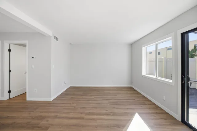 a view of an empty room with wooden floor and a window