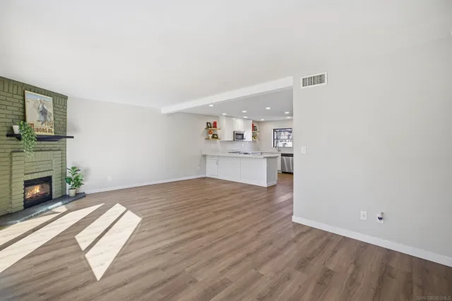 a view of empty room with wooden floor and fireplace
