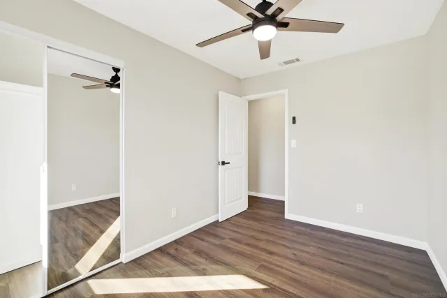 a view of a room with wooden floor and ceiling fan