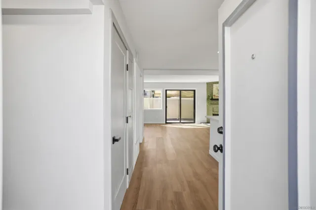 a view of a hallway with wooden floor and a bathroom