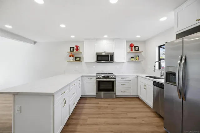 a kitchen with granite countertop a refrigerator stove top oven and sink