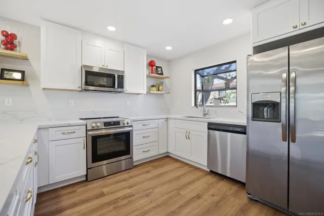 a kitchen with cabinets stainless steel appliances and wooden floor