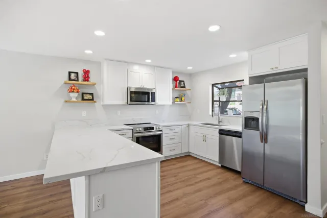 a kitchen with granite countertop stainless steel appliances a refrigerator sink and microwave