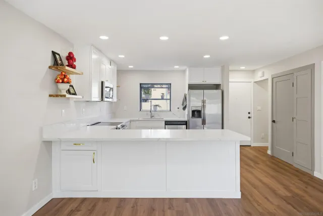 a large white kitchen with wooden floor and a sink