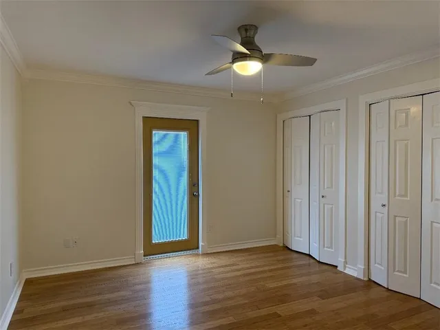 an empty room with wooden floor closet and windows