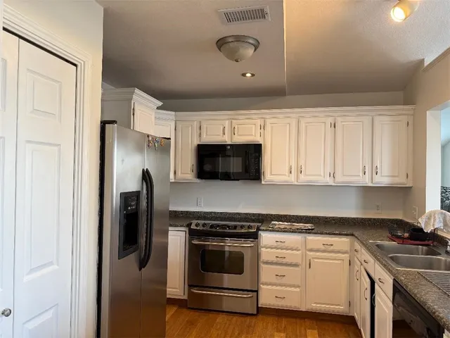 a kitchen with stainless steel appliances granite countertop a stove a refrigerator and a microwave