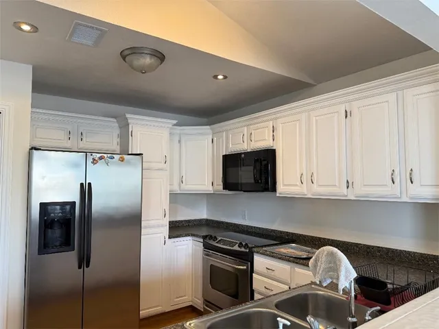 a kitchen with stainless steel appliances granite countertop a refrigerator a stove and a sink