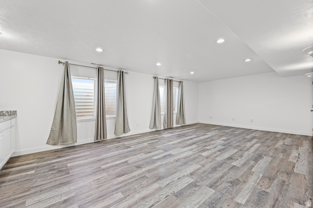 5525 Hampton Way Stansbury Park, UT 84074 - Photo 21 of 35 Spacious room featuring wood-finish flooring, white walls, recessed lighting, and multiple windows with blinds