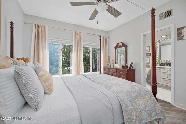 a bedroom with a bed chandelier and a large window