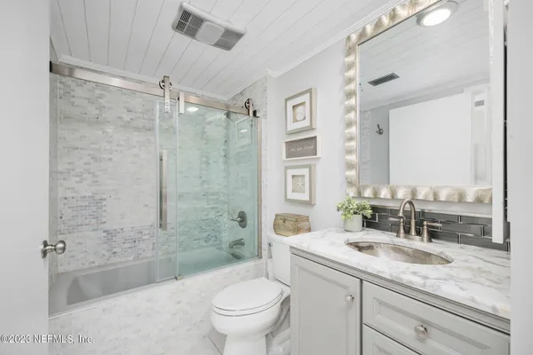a bathroom with a granite countertop sink toilet mirror and bathtub