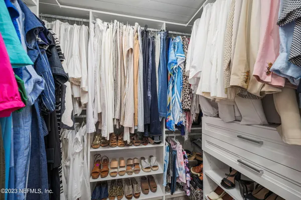 a view of walk in closet with clothes and shoes