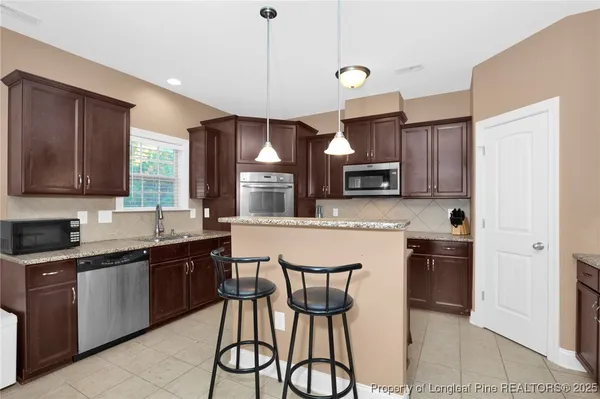 a kitchen with stainless steel appliances granite countertop a sink a stove a refrigerator cabinets and chairs