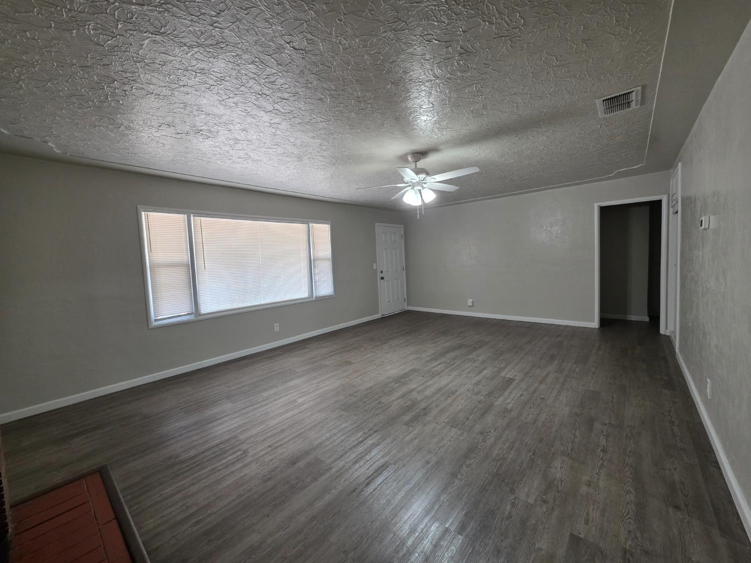 1416 Tully Road Modesto, CA 95350 - Photo 5 of 35 an empty room with wooden floor and windows