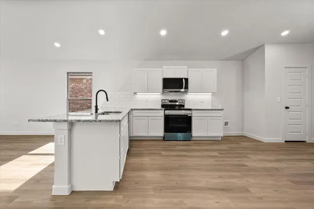 a kitchen with stainless steel appliances granite countertop a stove a sink and a refrigerator