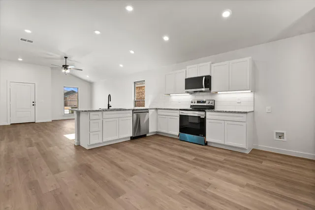 a kitchen with stainless steel appliances a sink stove and cabinets