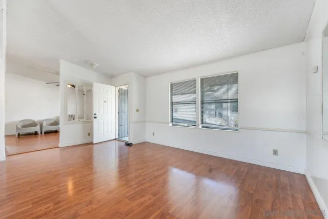 a view of an empty room with a window and wooden floor
