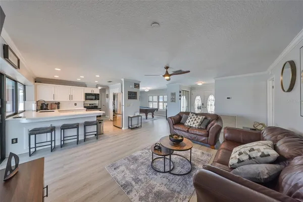 a living room with furniture kitchen view and a wooden floor