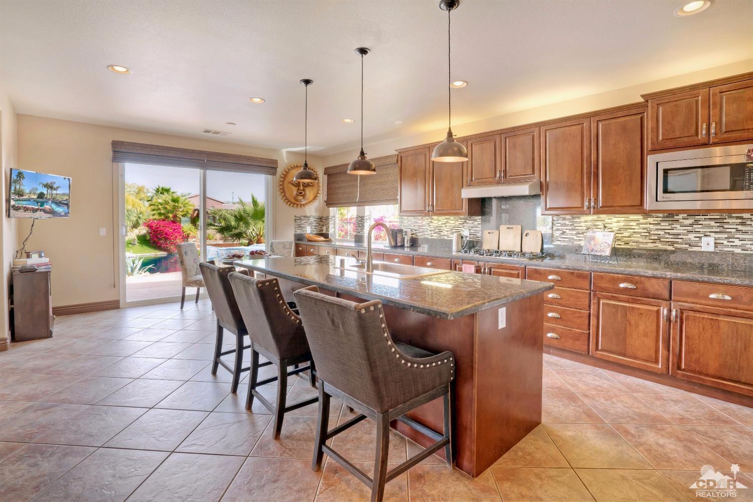 10 Via Santa Ramona Rancho Mirage, CA 92270 - Photo 46 of 78 a dining hall with stainless steel appliances kitchen island granite countertop a table chairs and a refrigerator