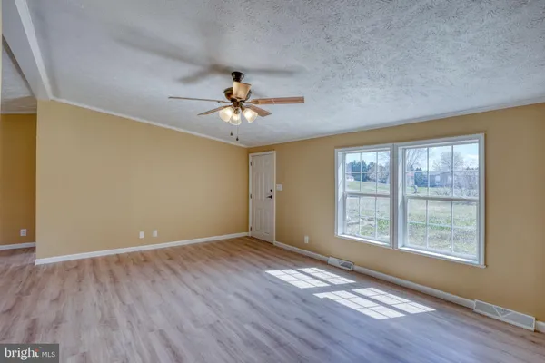 a view of an empty room with a window and wooden floor