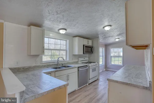 a kitchen with sink a microwave and cabinets