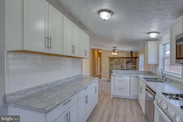 a kitchen with stainless steel appliances granite countertop a stove a sink dishwasher and a refrigerator with wooden floor