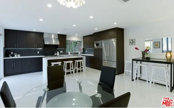 a kitchen with stainless steel appliances a refrigerator a sink a stove a dining table and chairs