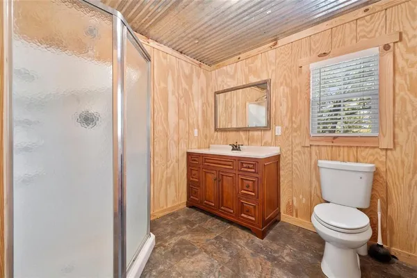 a bathroom with a granite countertop toilet a sink a mirror and a shower