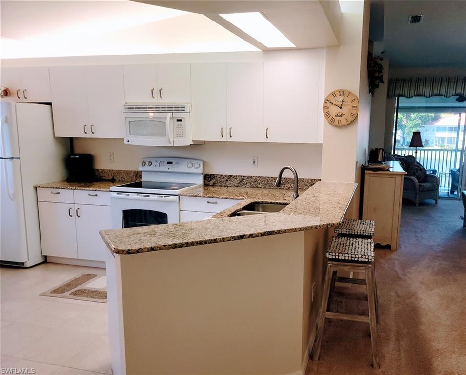 7435 Plumbago Bridge Road, Unit K201 Naples, FL 34109 - Photo 6 of 17 a kitchen with stainless steel appliances granite countertop a sink stove and refrigerator