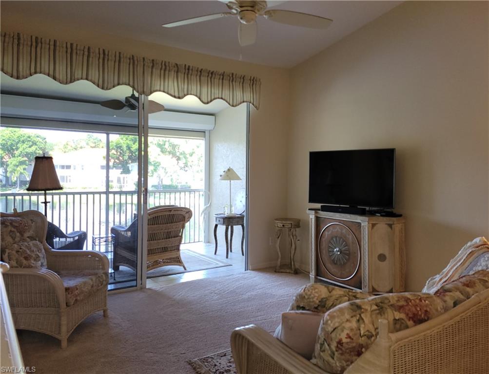 7435 Plumbago Bridge Road, Unit K201 Naples, FL 34109 - Photo 9 of 17 a living room with furniture a flat screen tv and a floor to ceiling window