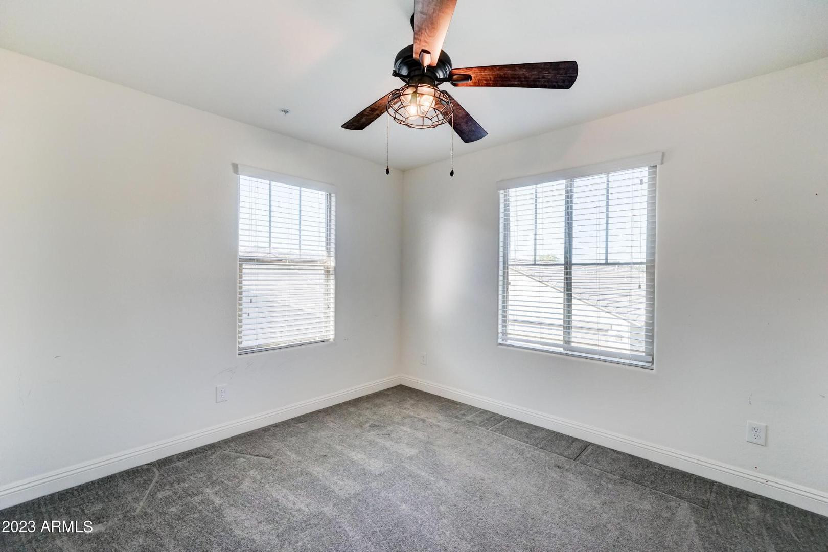 2297 North Alsap Road Buckeye, AZ 85396 - Photo 19 of 36 an empty room with chandelier fan and windows