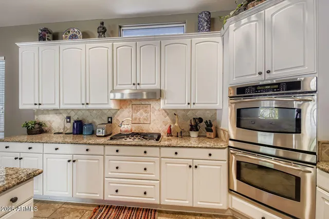 a kitchen with granite countertop white cabinets and stainless steel appliances